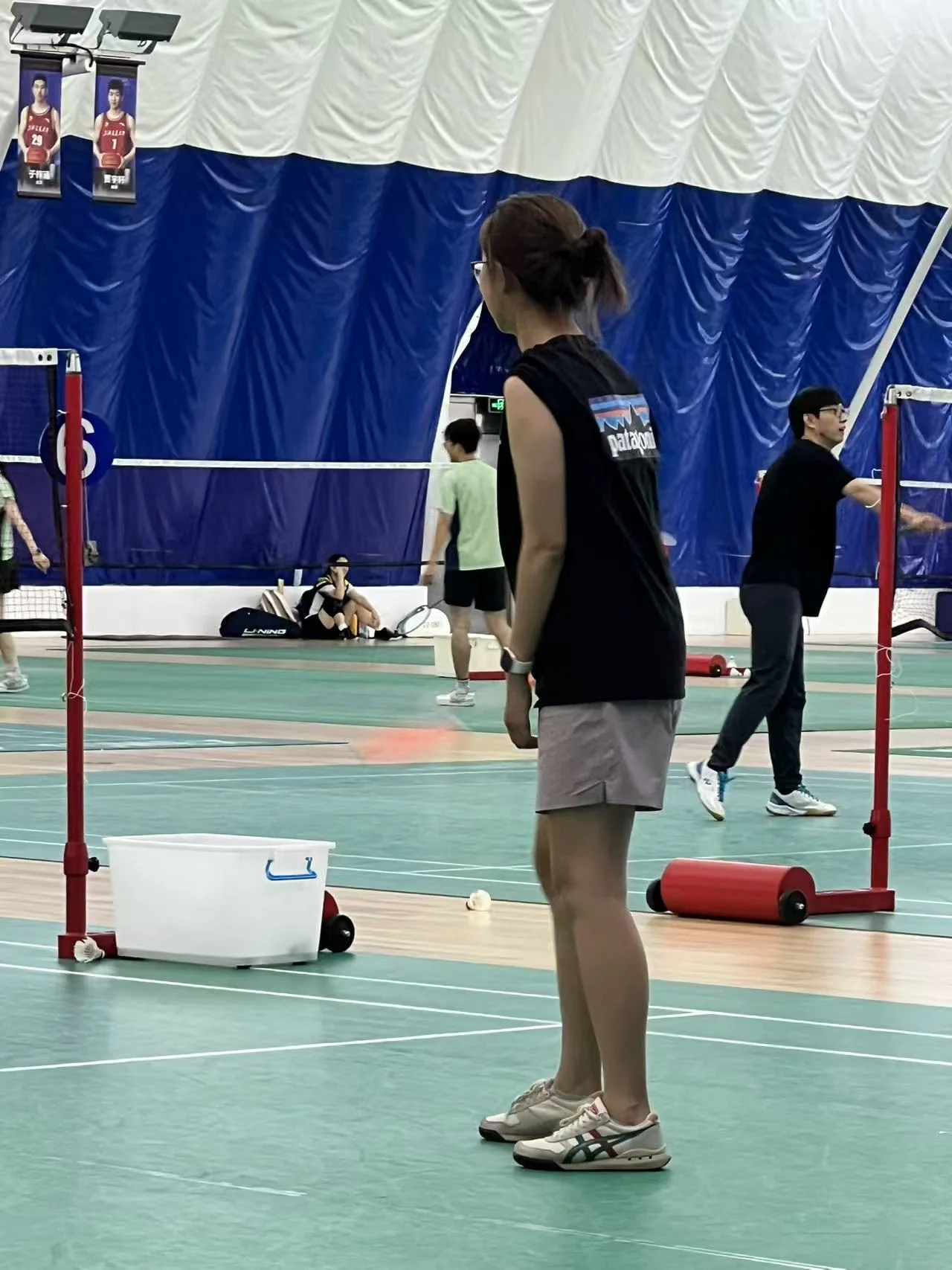 在羽毛球场上,穿着运动服准备接球。
